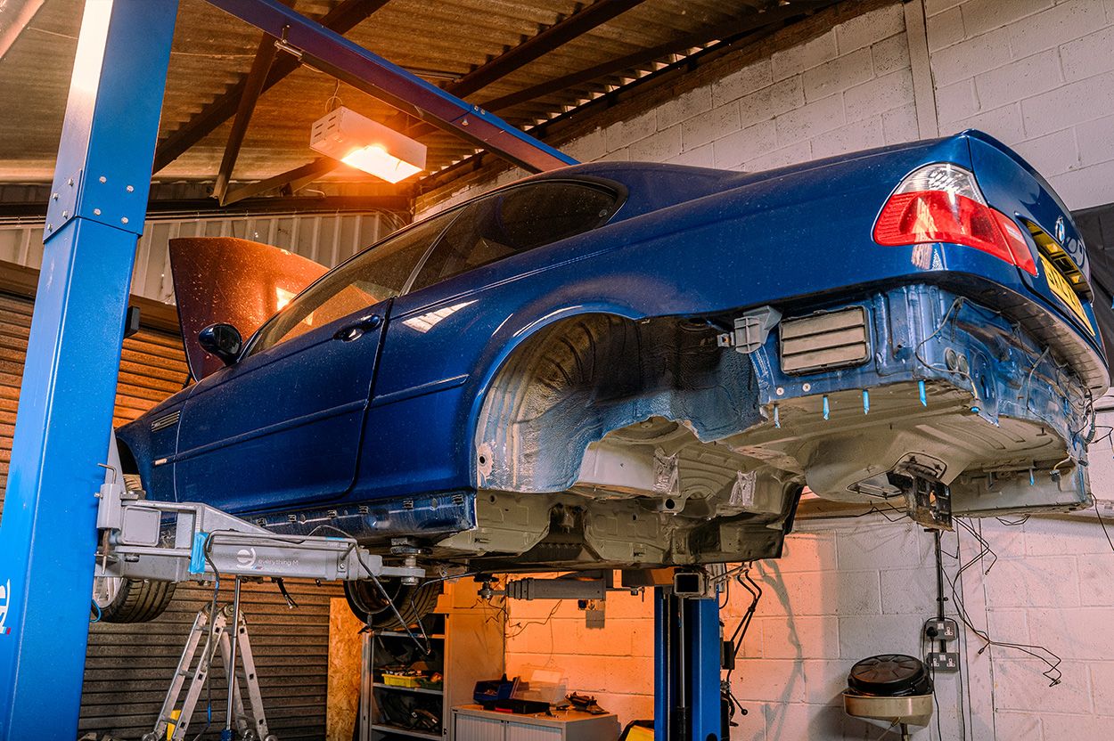 Rare Interlagos Blue BMW M3 on ramp in workshop while parts are being replaced